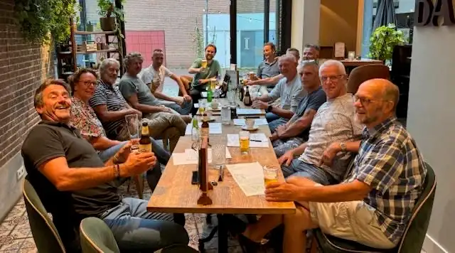 Vrijwilligers van de club aan een lange tafel tijdens het overleg