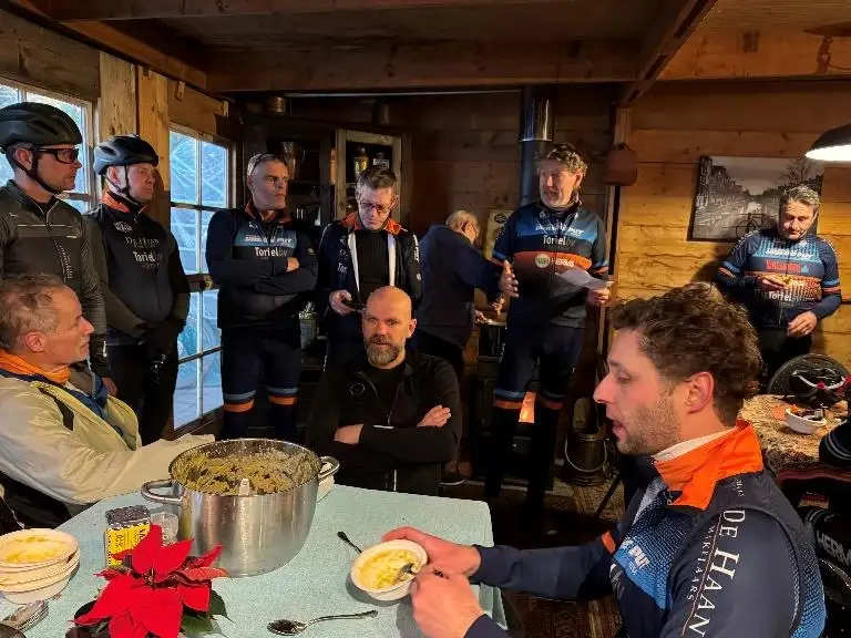 Deelnemers in clubkleding aan tafel met de erwtensoep na de Snertrit