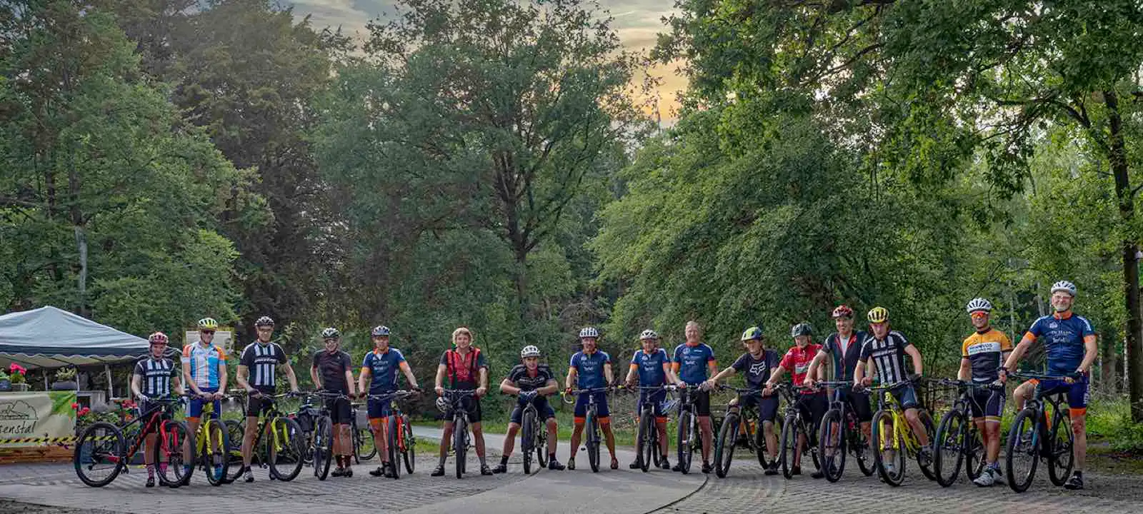 Groepsfoto van clubleden met hun mountainbikes op een bospad